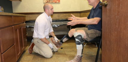 Practitioner fitting a leg brace on a seated patient